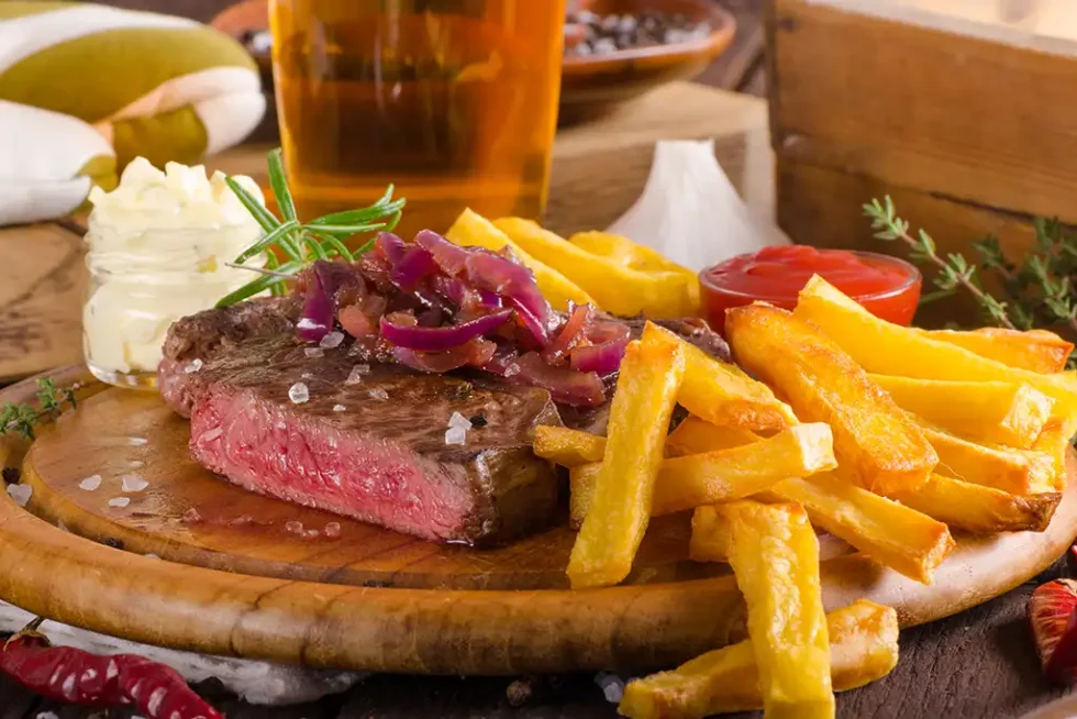 beef-steak-with-homemade-french-fries-beer-and-ta-2023-11-27 Steak with homemade chips and a pint at the Rose & Crown